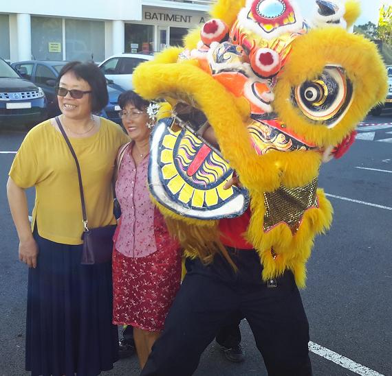 Madame Qi, entourée de Marita Liu Sing (une étudiante de l’Institut) et d’un lion chinois lors des festivités du nouvel an chinois de 2016 17.jpg